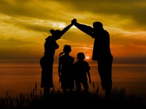 Mother and Father standing over two children, creating an arch by joining their hands.