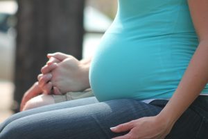 A Birth Mother sits on a bench holding hands with someone off screen.