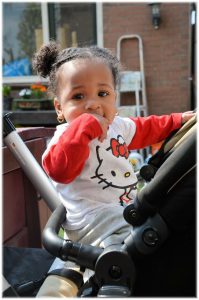 Black child sitting in a stroller wearing a Hello Kitty shirt.