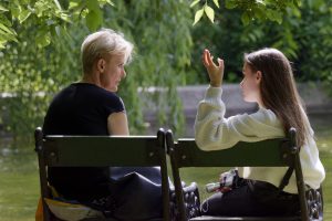 A mother sitting next to her daughter talking about her birth parents.