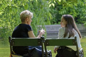 Mother and daughter talking on bench.