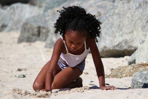 Young black girl playing on the beach.