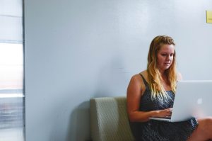 Woman sitting on couch with laptop on her lap creating an adoption plan.
