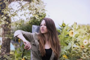 Young girl sitting in a field of flowers thinking about her unplanned pregnancy.