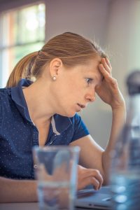 Woman looks sad while sitting at a counter with her head in her hand after dealing with rude questions.