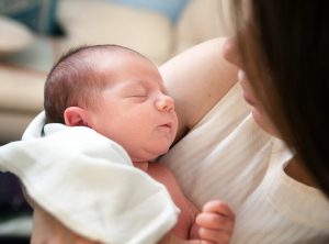 mother holding a newborn contemplating creating an adoption plan after birth.