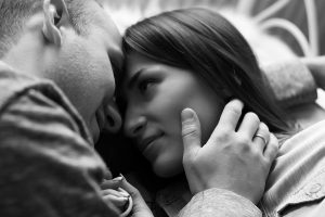 Saving for Adoption blog image. A man and woman embrace while laying down. Their foreheads are touching as they look into each other's eyes.