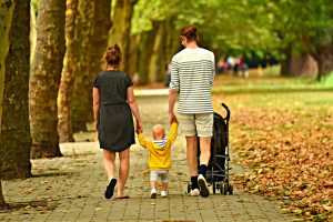 Foster Care Blog Image: A family of three walking down a brick sidewalk. The child is in the middle holding his parents' hands.