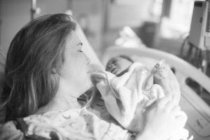 Maryland Adoption Agency Blog Image - A mother laying in a hospital bed holding her newborn baby.