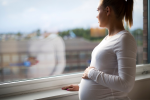 How Will Adoption Affect My Baby? A young pregnant woman looks out a window.